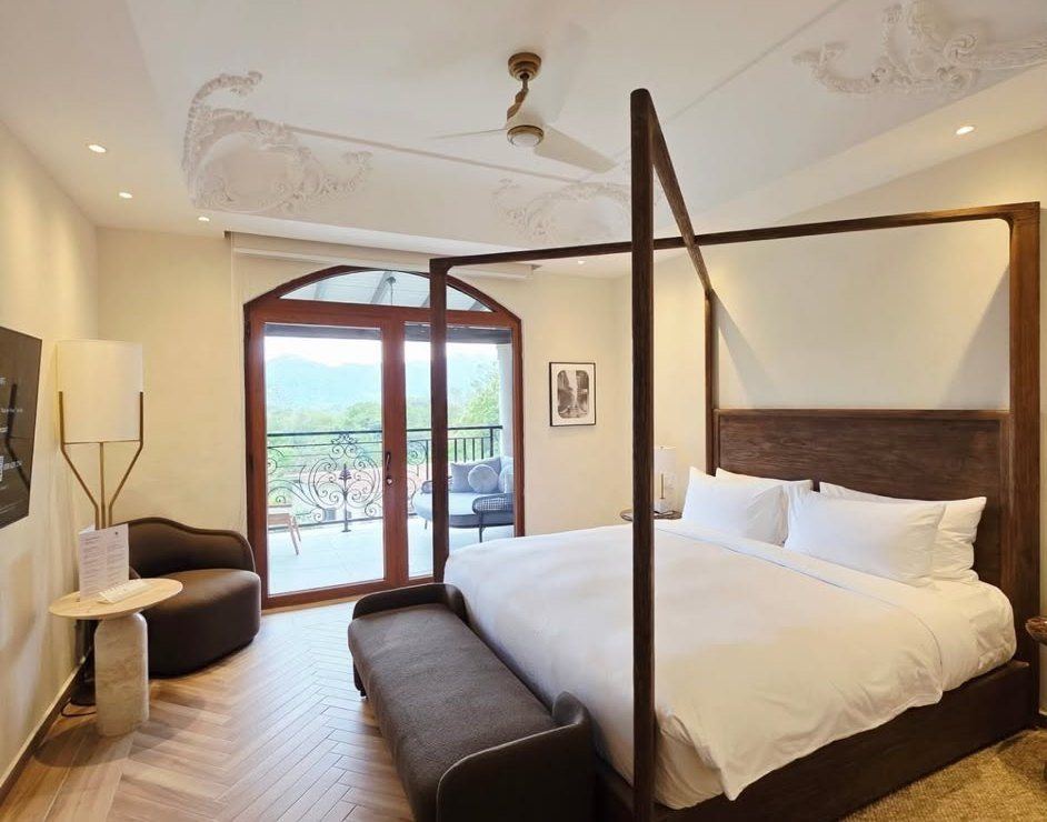 A bright bedroom with a four-poster bed and mountain view